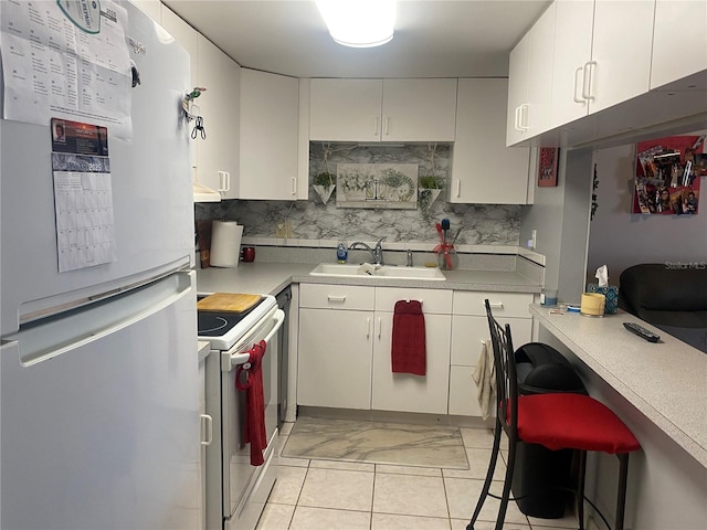 kitchen with light tile patterned flooring, sink, backsplash, white cabinets, and white appliances