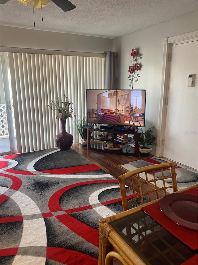 living room featuring ceiling fan, wood-type flooring, and a textured ceiling