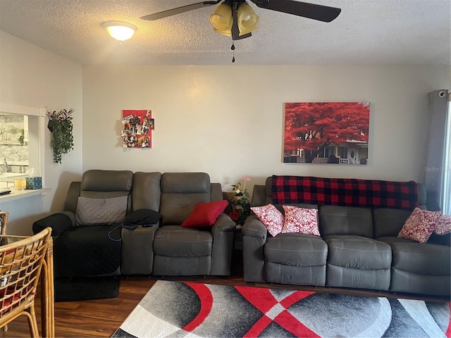 living room with ceiling fan, dark hardwood / wood-style floors, and a textured ceiling