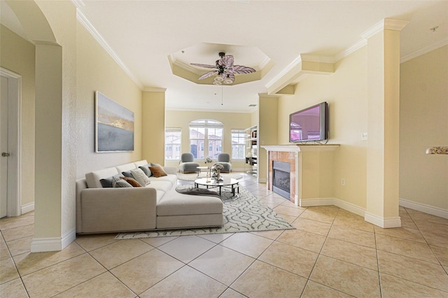 living room featuring crown molding, ceiling fan, light tile patterned floors, a tray ceiling, and a fireplace