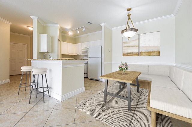 kitchen with white appliances, white cabinets, sink, hanging light fixtures, and kitchen peninsula