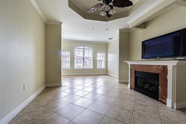 unfurnished living room with light tile patterned flooring, ceiling fan, crown molding, and a tiled fireplace