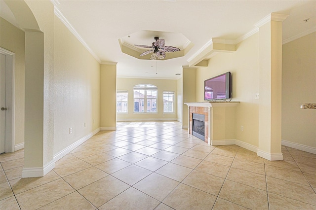 unfurnished living room with crown molding, a fireplace, a raised ceiling, ceiling fan, and light tile patterned flooring