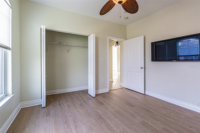 unfurnished bedroom with light hardwood / wood-style floors, a closet, multiple windows, and ceiling fan