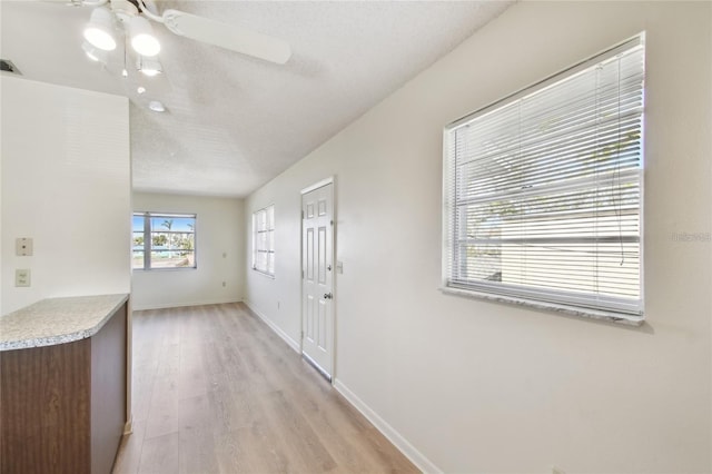 interior space with light wood-type flooring, a textured ceiling, and ceiling fan