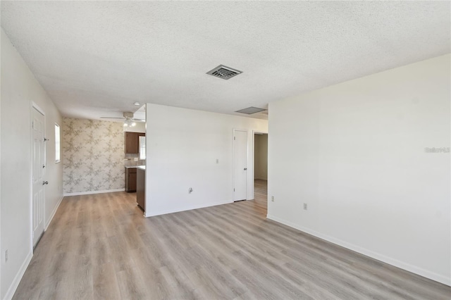 spare room featuring ceiling fan, light hardwood / wood-style flooring, and a textured ceiling