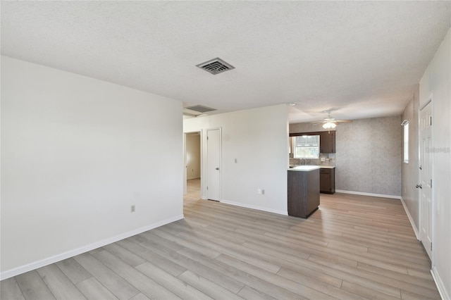 unfurnished living room featuring light wood-type flooring, a textured ceiling, and ceiling fan