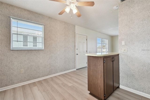 kitchen featuring light hardwood / wood-style floors, kitchen peninsula, ceiling fan, and a healthy amount of sunlight