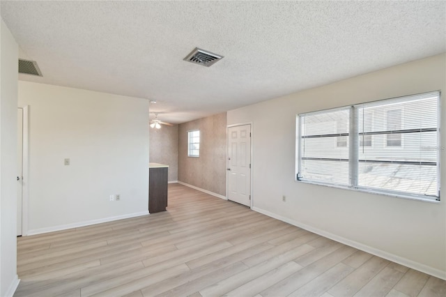 spare room featuring light wood-type flooring, a textured ceiling, and ceiling fan