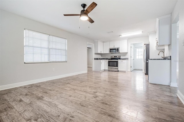 unfurnished living room with sink, ceiling fan, and light hardwood / wood-style flooring