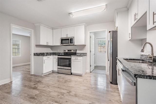 kitchen featuring white cabinetry, stainless steel appliances, sink, and dark stone countertops