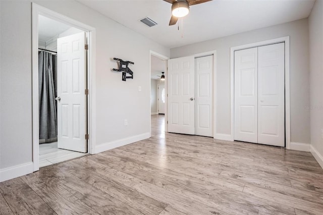 unfurnished bedroom with multiple closets, ceiling fan, ensuite bathroom, and light hardwood / wood-style flooring