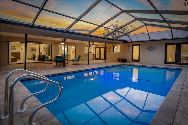 pool at dusk with ceiling fan, a lanai, and a patio area