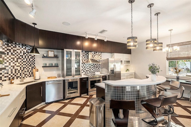 kitchen featuring wall chimney range hood, stainless steel appliances, wine cooler, sink, and backsplash