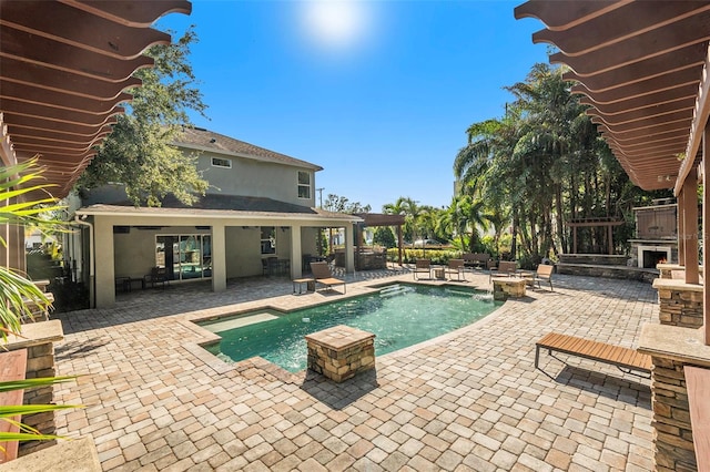 view of pool with exterior fireplace and a patio