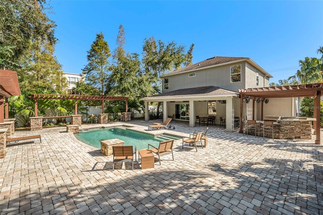 view of pool featuring a patio, a pergola, exterior kitchen, and an outdoor bar