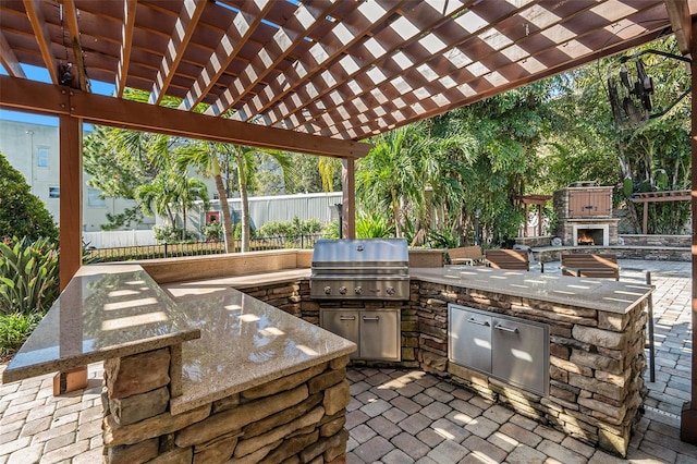 view of patio with an outdoor stone fireplace, an outdoor kitchen, grilling area, and a pergola