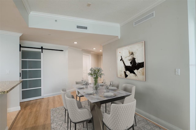 450 Knights Run Ave Unit 605, Tampa, FL 33602 - dining area with crown molding, a barn door, a textured ceiling, and light wood-type flooring