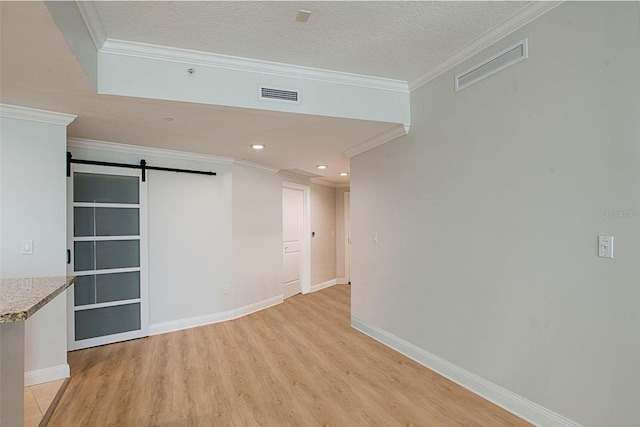 450 Knights Run Ave Unit 605, Tampa, FL 33602 - unfurnished room featuring ornamental molding, a barn door, a textured ceiling, and light hardwood / wood-style floors