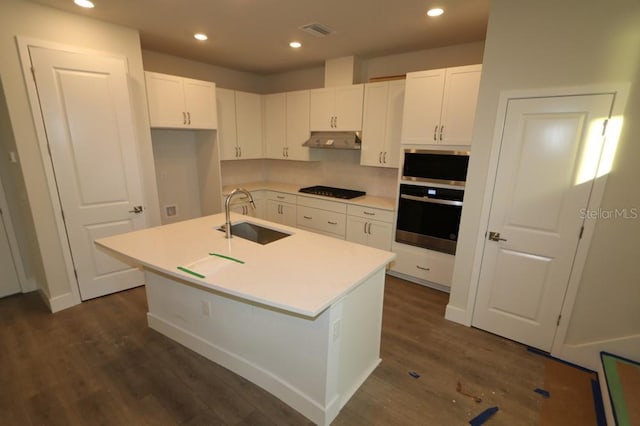 kitchen featuring a kitchen island with sink, a sink, oven, and under cabinet range hood