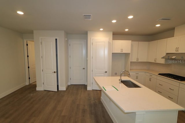 kitchen featuring a center island with sink, black gas cooktop, light countertops, under cabinet range hood, and a sink