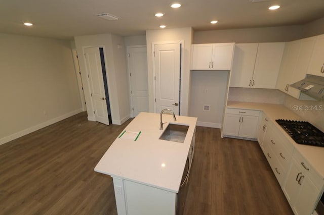 kitchen with black gas cooktop, white cabinets, light countertops, and a center island with sink