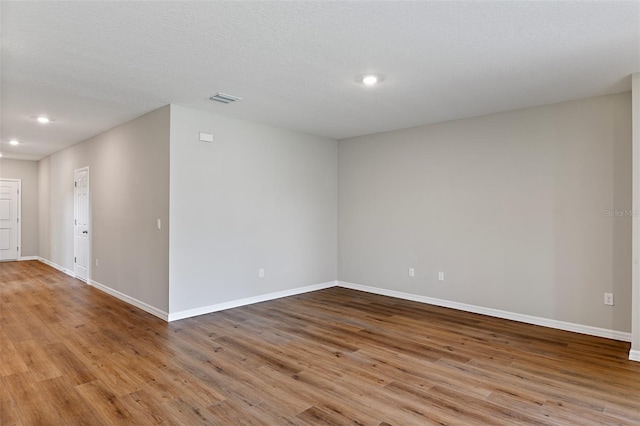 spare room with a textured ceiling and light wood-type flooring