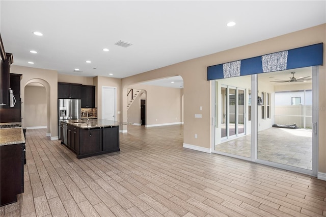 kitchen featuring dark brown cabinets, sink, a center island with sink, and light hardwood / wood-style flooring