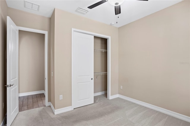 unfurnished bedroom with light carpet, a closet, and ceiling fan