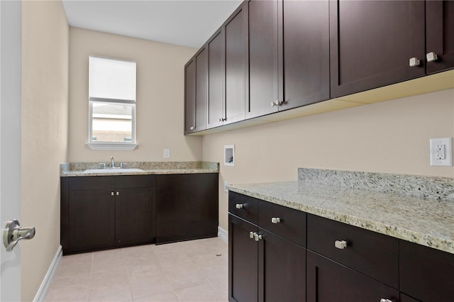 clothes washing area with washer hookup, sink, light tile patterned floors, and cabinets