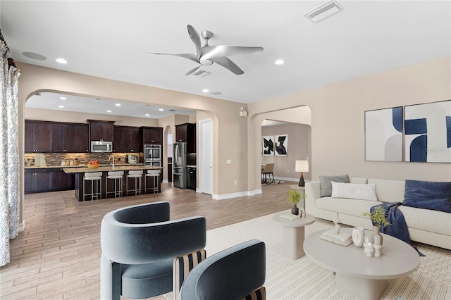 living room with ceiling fan, sink, and light hardwood / wood-style floors