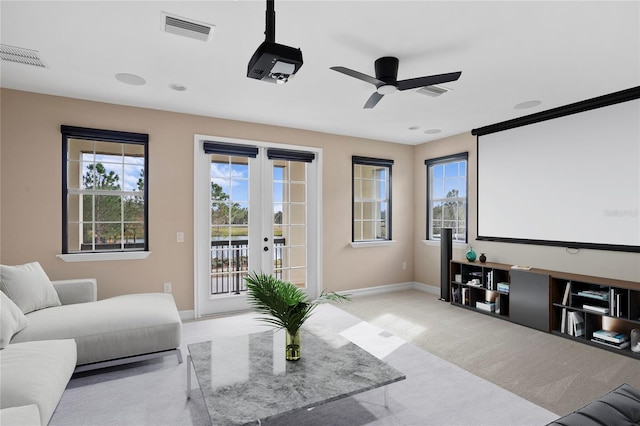 carpeted cinema with ceiling fan and french doors