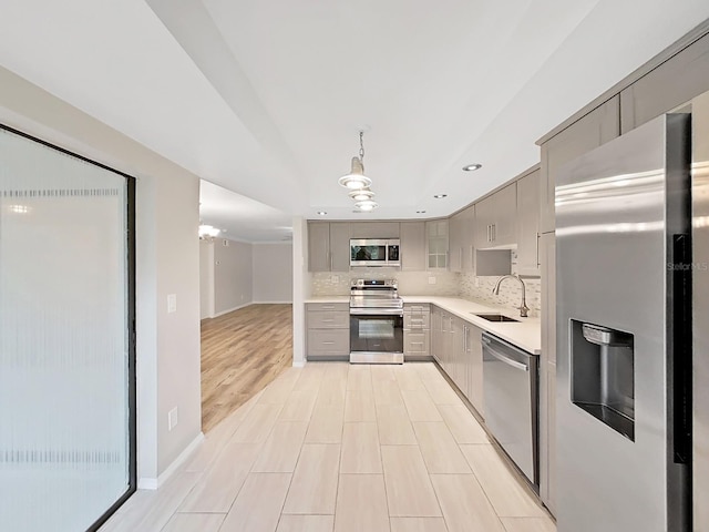 kitchen featuring decorative light fixtures, stainless steel appliances, sink, backsplash, and gray cabinetry