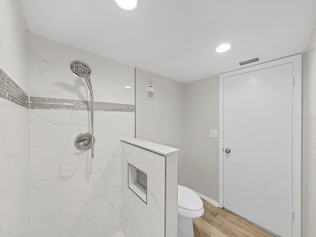 bathroom with hardwood / wood-style floors, tiled shower, and toilet