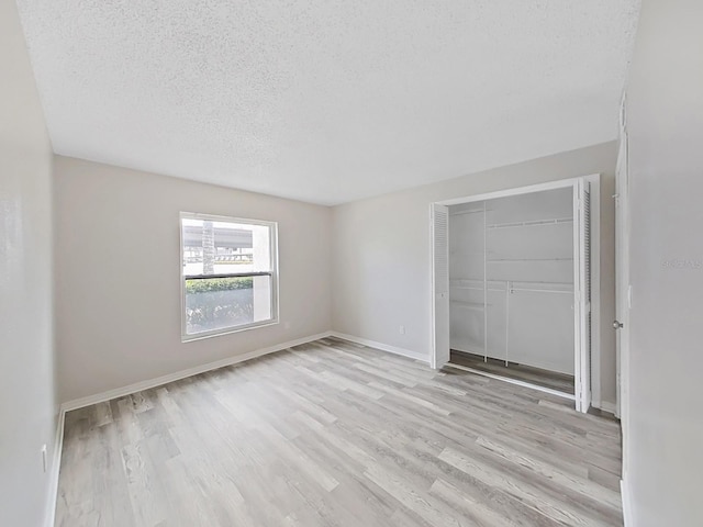 unfurnished bedroom featuring a closet, light hardwood / wood-style floors, and a textured ceiling