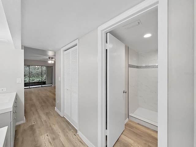 bathroom with vanity, ceiling fan, tiled shower, and hardwood / wood-style floors