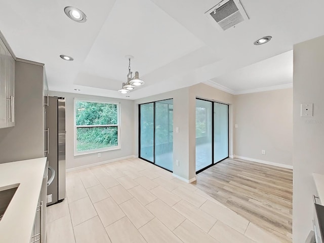 interior space with a raised ceiling, ornamental molding, and light hardwood / wood-style floors