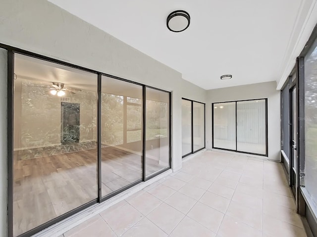 unfurnished sunroom with ceiling fan