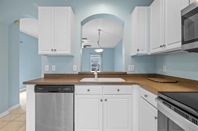 kitchen with light tile patterned floors, sink, stainless steel appliances, white cabinets, and kitchen peninsula