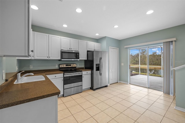 kitchen with stainless steel appliances, white cabinetry, sink, and light tile patterned floors