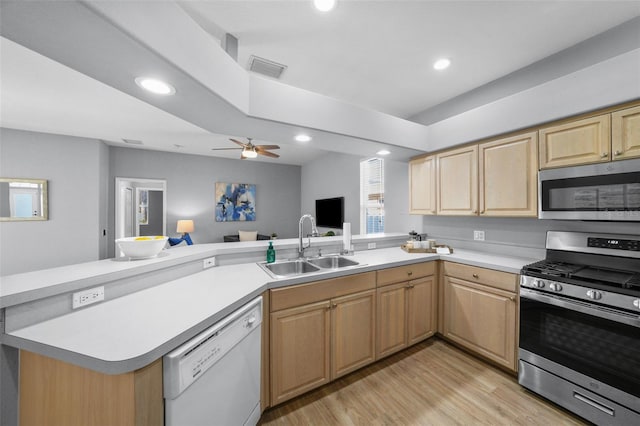 kitchen featuring light brown cabinetry, sink, kitchen peninsula, stainless steel appliances, and light hardwood / wood-style flooring