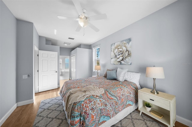 bedroom featuring ceiling fan, ensuite bathroom, hardwood / wood-style floors, and a closet