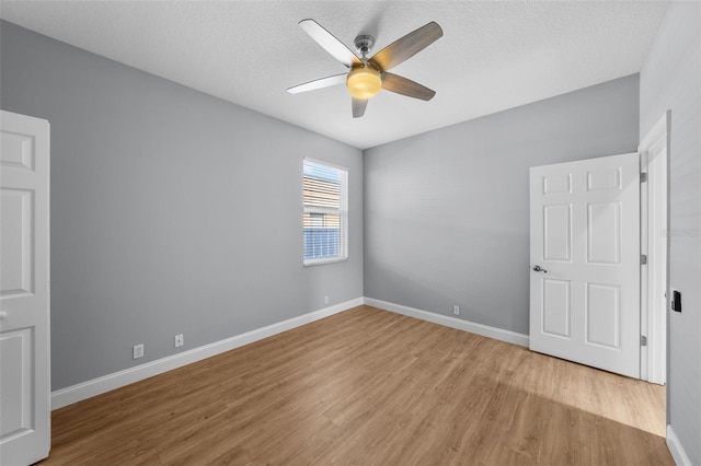 spare room with ceiling fan, light hardwood / wood-style flooring, and a textured ceiling