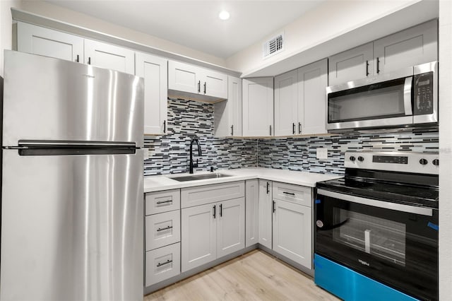 kitchen featuring light hardwood / wood-style floors, sink, backsplash, and appliances with stainless steel finishes