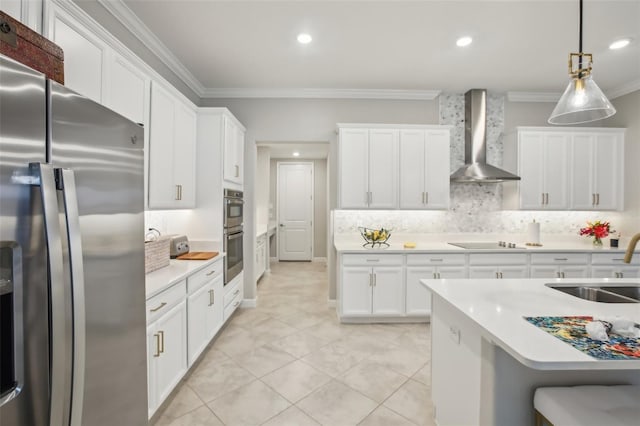 kitchen with sink, hanging light fixtures, appliances with stainless steel finishes, wall chimney range hood, and white cabinets