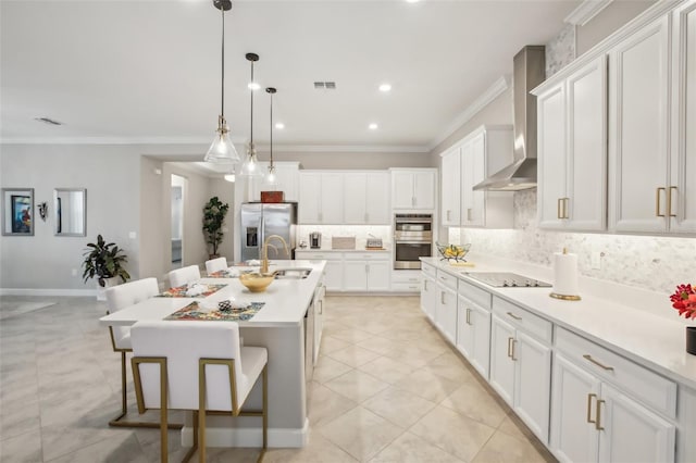 kitchen featuring white cabinetry, appliances with stainless steel finishes, a kitchen island with sink, decorative backsplash, and wall chimney range hood