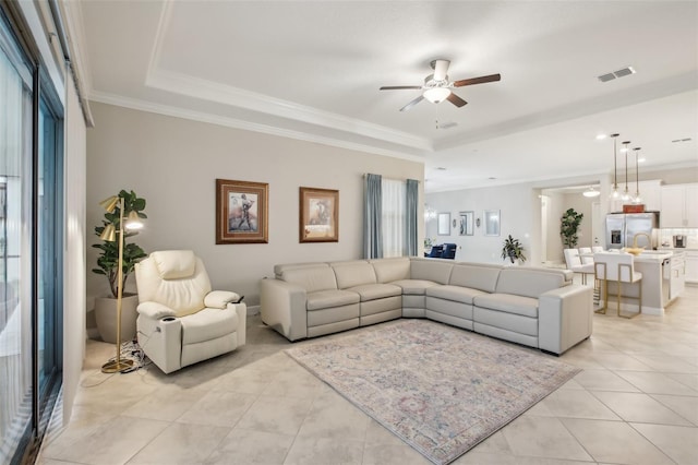 tiled living room featuring ornamental molding, ceiling fan, and a tray ceiling