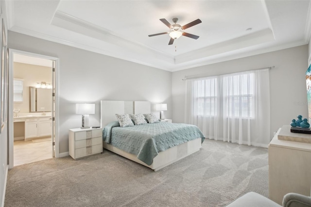 bedroom featuring connected bathroom, light colored carpet, a raised ceiling, and ceiling fan