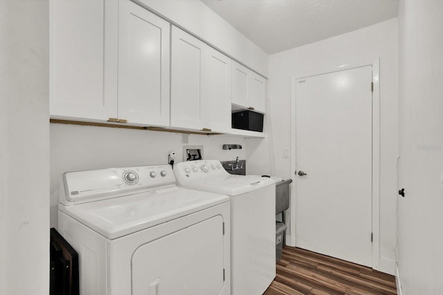 laundry room featuring cabinets, a textured ceiling, washing machine and clothes dryer, and dark hardwood / wood-style flooring