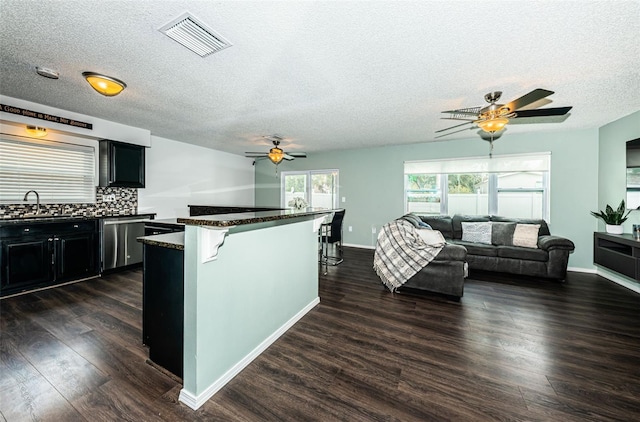 kitchen featuring sink, dark wood-type flooring, dishwasher, a kitchen breakfast bar, and tasteful backsplash